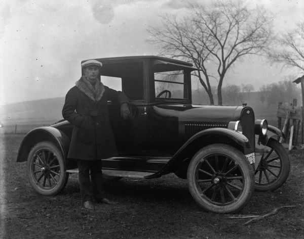 Edgar Krueger posing next to a 1923 Chevy Coupe.
