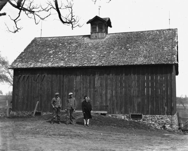 Lester Turke, Edgar Krueger, and Florentina Krueger posing together in front of an old barn on the Krueger farm.