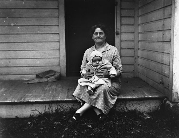 Florentina Krueger holding her granddaughter, Shirley, in her lap as she sitting on the edge of the porch.