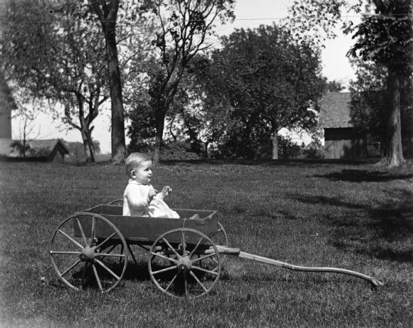 Shirley Krueger sitting in a small wagon in the yard.