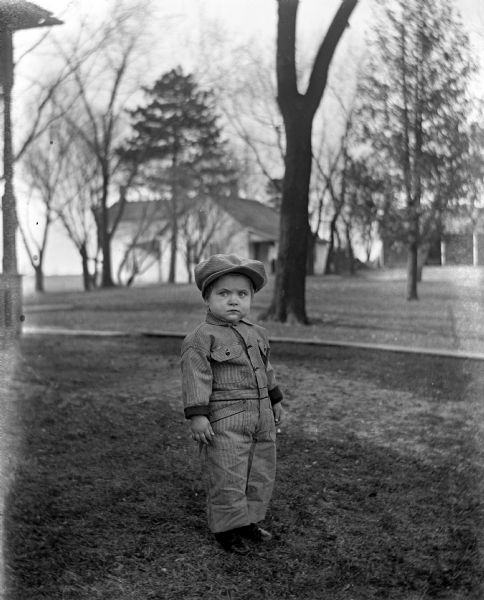 Outdoor portrait of Shirley Krueger standing in the yard wearing coveralls and a cap.