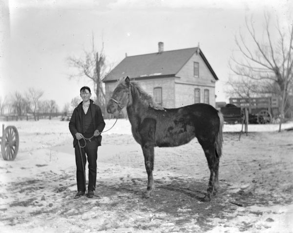 Ed Wendorf standing with a horse in front of the Wendorf home.