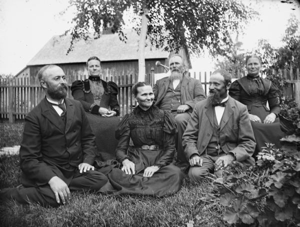Outdoor group portrait of the six children of William Krueger. In the front row sitting on the grass are, from left: Henry, Minnie, and Albert. In the back row sitting on chairs, from left: Emilie, August, and Bertha.