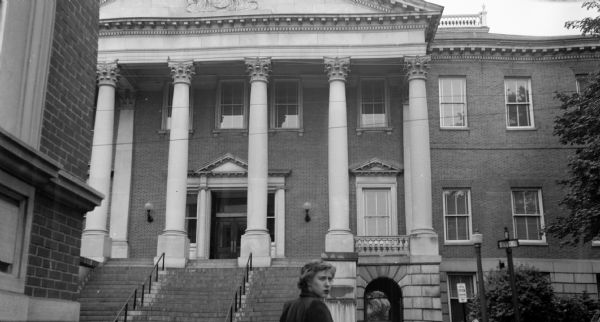 View of the Maryland State House from the street. A woman stands in front of the camera looking back to her right.