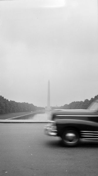 View of the Washington Monument from the end of the reflecting pool. A car is in the right foreground.