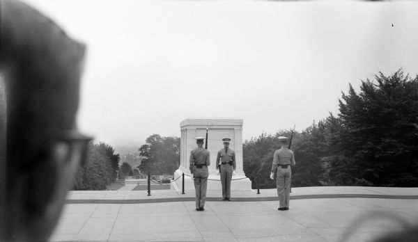 Changing of the guard at the Tomb of the Unknown soldier. The back of a man's head is in the foreground on the left.