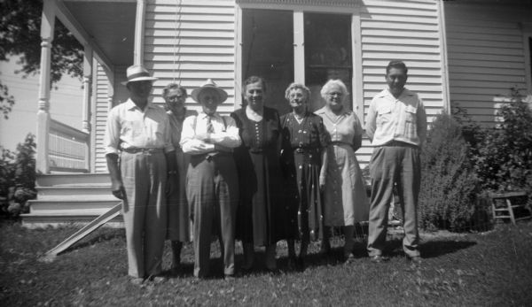 Group portrait of Florentina, Elna, and Robert Krueger with two other couples standing in front of a home. Florentina, Elna, and Robert stand on the far right.