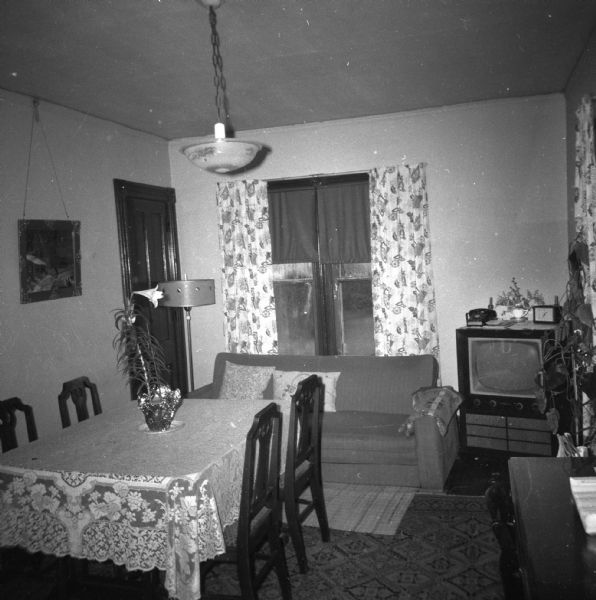 View of the dining room in the Krueger home. A television and couch sit behind the dining room table near a window.