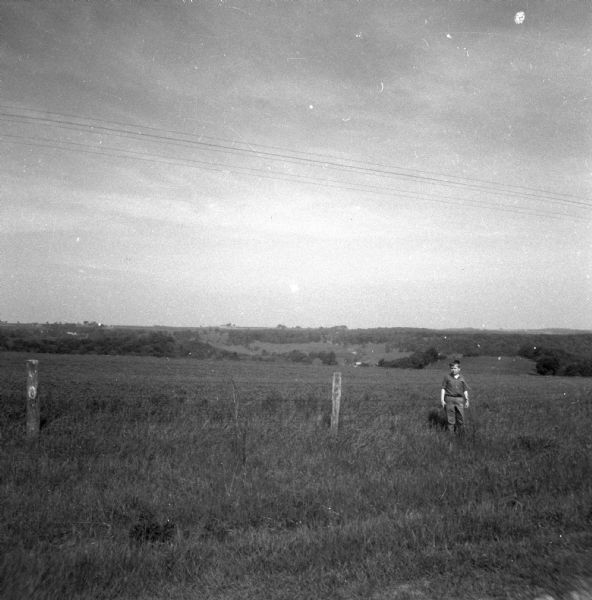Glenn Oestreich standing next to a fence along a field with a valley in the background.
