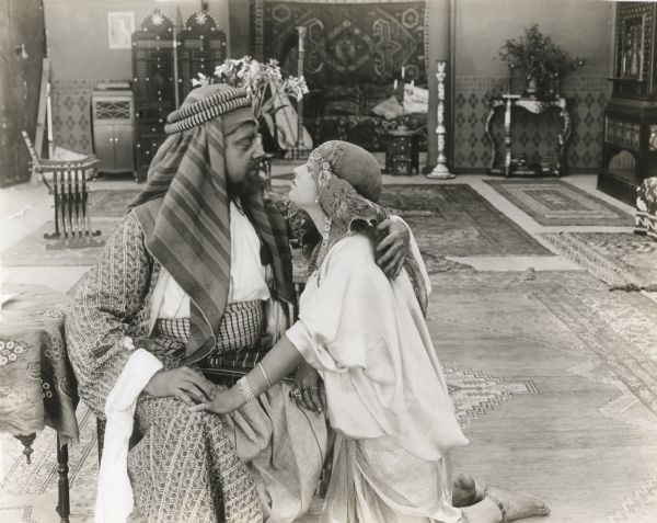 In Algiers, Hafsa (played by Lenore Ulric) is on her knees in supplication to her father, Sidi Malik (Herschell Mayall). The caption typed on the back of the print reads: "You give me everything, father, except—freedom."