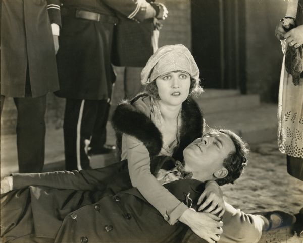 Florrie Ricks (played by Agnes Ayres), the daughter of a shipowner, attends to Matt Peasley (Thomas Meighan), a seaman who lies unconscious in her lap in a San Francisco street in a scene still from "Cappy Ricks."