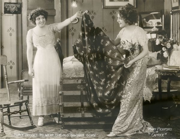 Edith Henderson (played by Boots Wall) and Mercy Baxter (Mary Pickford) in a scene still from "Caprice" (Lasky 1913). A caption written on the back of the print reads: "I am going to meet him in the rose garden and I am going to wear that old gingham gown."