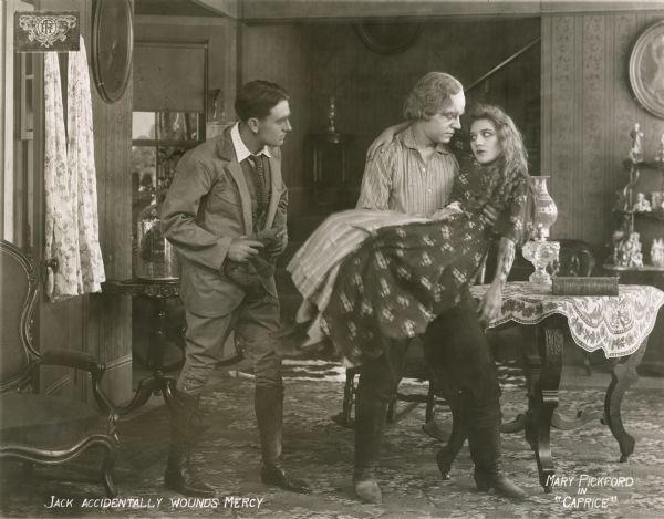 The wealthy playboy Jack Henderson (played by Owen Moore) has accidentally shot Mercy Baxter (Mary Pickford) in the arm and has carried her to her home in the mountains. In this scene still, she is in the arms of her father, Jim Baxter (played by Ogden Crane).