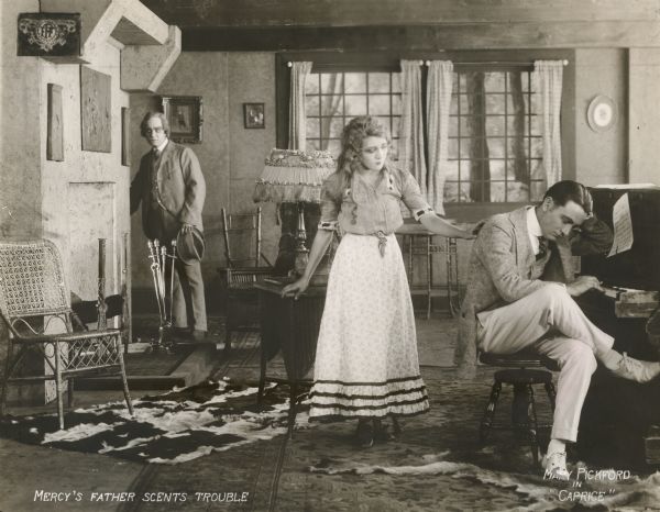 Pausing by the door of his mountain cabin, Jim Baxter (played by Ogden Crane) notices that his daughter Mercy (Mary Pickford) and the wealthy visitor from the city, Jack Henderson (Owen Moore), have feelings for each other. The caption printed on the face of the publicity photograph reads: "Mercy's father scents trouble."