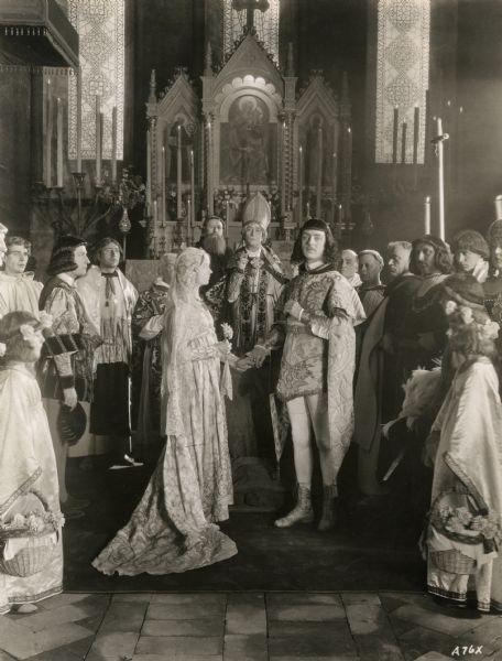 Romola (played by Lillian Gish) and Tito Melema (William Powell) standing before the altar during their wedding in a scene still for Henry King's production "Romola" (Inspiration 1925). This silent film is based upon George Eliot's 1863 novel set in Renaissance Italy.