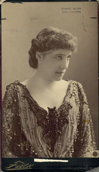 Half-length publicity portrait of Lillie Langtry wearing a dress decorated with a large bat at the neckline.