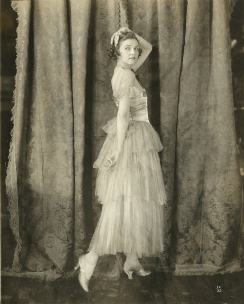 Irene Castle in a gauzy tulle and satin dress in a full-length pose in a publicity photograph for the silent film "Patria" (International 1917).
