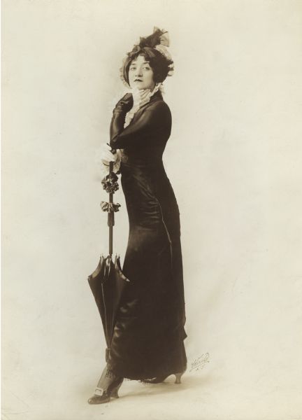 Dorothy Jardon wears chic black satin mourning clothes and carries a black parasol in a publicity photograph for "A Winsome Widow," a musical comedy that played at the Ziegfeld Moulin Rouge.