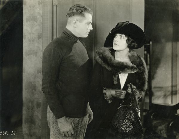 The boxer Pat Glendon, Jr. (played by Reginald Denny) and socialite Maude Sangster (Mabel Julienne Scott) glare at each other in a scene still from "The Abysmal Brute" (Universal 1923). She is very well-dressed with a fancy purse, elaborate gloves, and a fox stole.