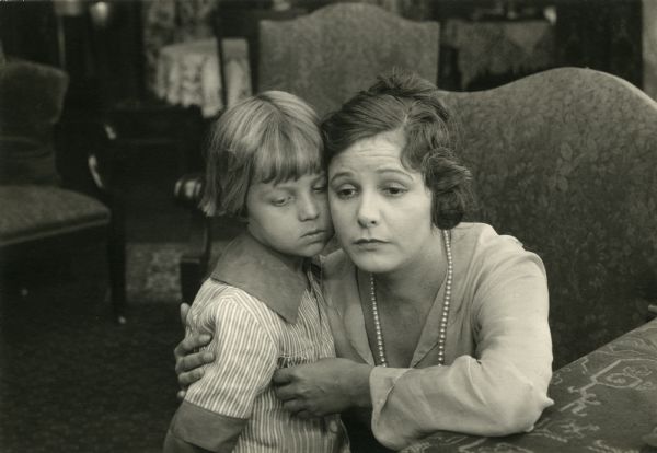 The child actor George Stone is embraced by Norma Talmadge in a scene still perhaps from the 1916 silent film "Martha's Vindication." Other films in which the two actors appeared together were "The Children in the House" and "Going Straight."