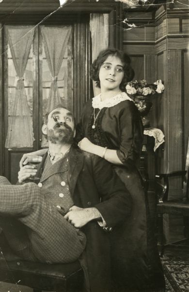 William Robert Daly, leaning back in a chair with a wine glass and a cigar, and Ethel Grandin in a scene still attributed to the silent short "Across the Plains," but which may well be connected to "Uncle's Visit," "The Kid and the Sleuth," or some other film they acted in together.