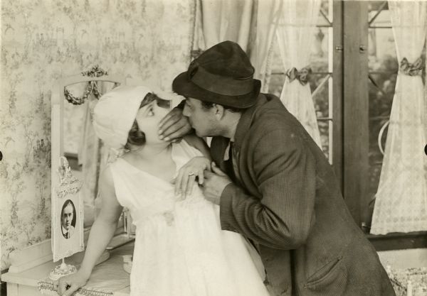 The robber Jimmy Briggs (played by Eugene Pallette) is stifling the cries of Grace Remington (Norma Talmadege) in this scene still from the silent feature film "Going Straight."