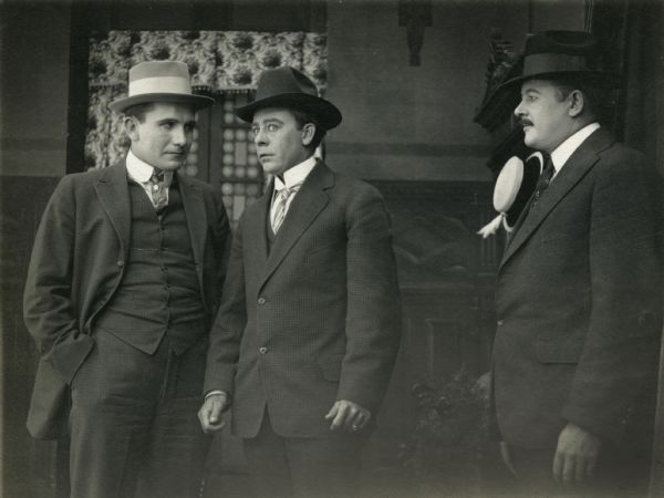 William Lowrey (left), Vester Pegg, looking quite worried at center, and an unknown actor in "Added Fuel." They wear suits, hats, and stiff collars.