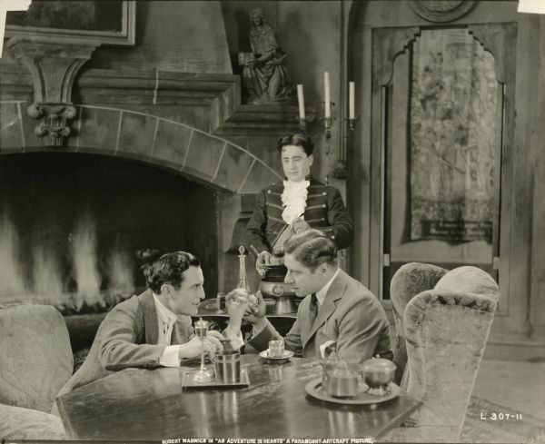 Count Fieramondi (played by Juan de la Cruz) and Captain Dieppe (Robert Warwick) sit at a table in the count's castle having a man to man talk. Behind them a butler is preparing to serve a drink.