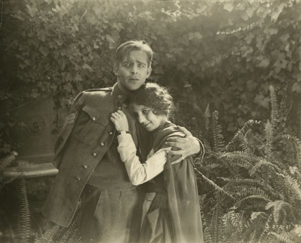 Larry Young (played by Wallace Reid in the uniform of a sergeant in the Canadian army) embraces Elaine Debaux (Ann Little in a nurse's cape) in a scene still from "Alias, Mike Moran." Reid's character has lost his right arm because of a battle wound.