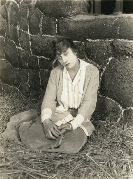 Kitty Gray (played by Grace Cunard) sits forlornly on the straw in a dungeon in the kingdom of Grahaffen in a scene still from Episode 7 "Between Two Fires" of the Universal serial "The Broken Coin."