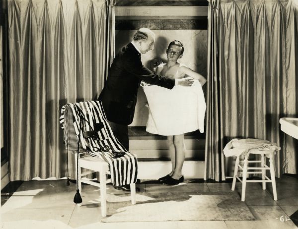 Arnold Lucy (playing a valet) wraps a towel around Wesley Barry (Speck Brown) who has just gotten out of the bath in a scene still from "School Days" (Warner, 1921).