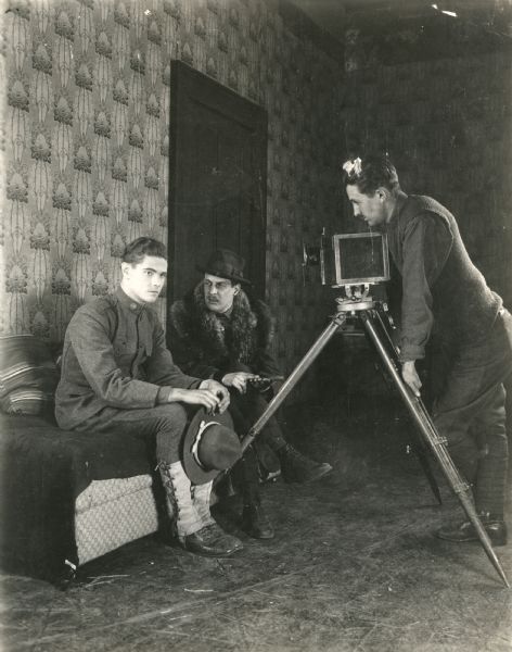 The actor Paul Kelly (playing Hank Simpson) sits next to director Edward H. Griffith in front of a cameraman and his Debrie motion picture camera in a production still from "Fit to Fight." This was an anti-venereal disease film produced by the U.S. War Department which was lengthened, re-edited, and released again in 1919 as "Fit to Win."