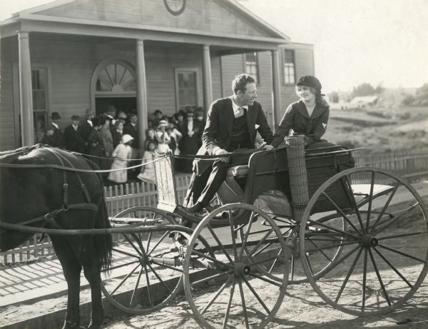 Original caption:
"Mary Miles Minter and her director James Kirkwood in the street of the little old New England Village constructed behind the American Film Company's studios at Santa Barbara, California, used in the filming of 'Environment' Miss Minter's next Mutual star production."