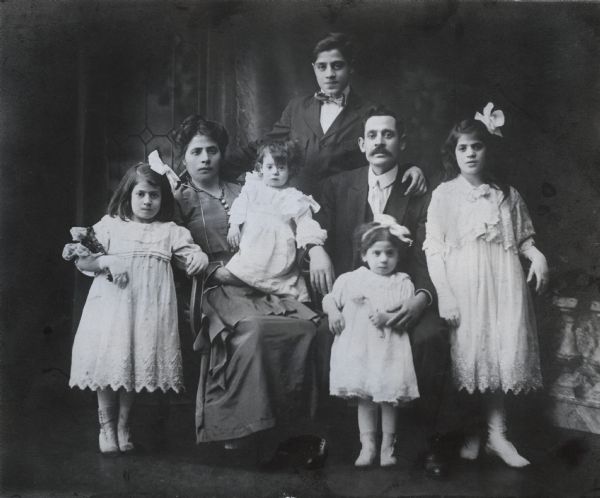 Studio portrait of Mr. Louis Biondolillo and his wife seated with their five children around them. From left to right the girls are Mary, Lena, Rose, Paulina, and Emily. Behind his parents stands Gaspare Biondolillo who would become the well-known stage and motion picture actor Jack La Rue.