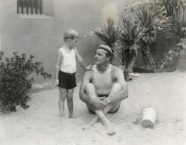 Original caption: "Wally Reid and Billy ready for a swimming lesson in the pool at the beautiful Reid home."