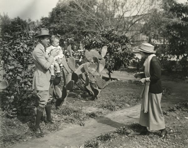 Original caption: "Mr. Warner's spare moments are divided between cleansing his car and photographing his baby while Mrs Warner devoted herself to photographing baby and adding to baby's well-filled Kodak books. Joan is 14-months-old and has fourteen large Kodak books already to her credit."
