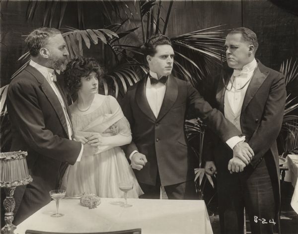 Dick Mason (played by George Walsh) confronts the corrupt, monocle-wearing Count Vortsky (Edward Cecil) as Princess Alexia (Enid Markey) and Baron Maravitch (Count Fritz von Hardenberg) watch in a scene still from the 1917 Fox production "The Yankee Way."