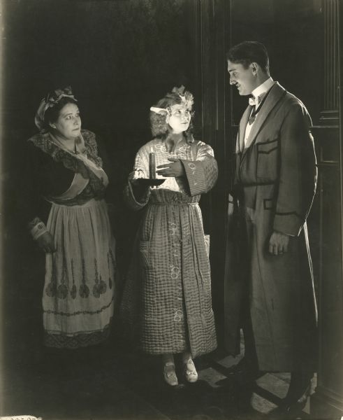 Accompanied by a maid, Princess Pat, holding a candle, meets King Eric in a dark hallway. Pat was played by Gladys Leslie and the King by  J. Frank Glendon in "The Wooing of Princess Pat," a Vitagraph production of 1918.