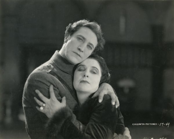 Prince Michael Orbeliana (played by Lou Tellegen in a rough wool  military coat) warmly embraces Marcia Warren (Geraldine Farrar) in this scene still from "The World and Its Woman."