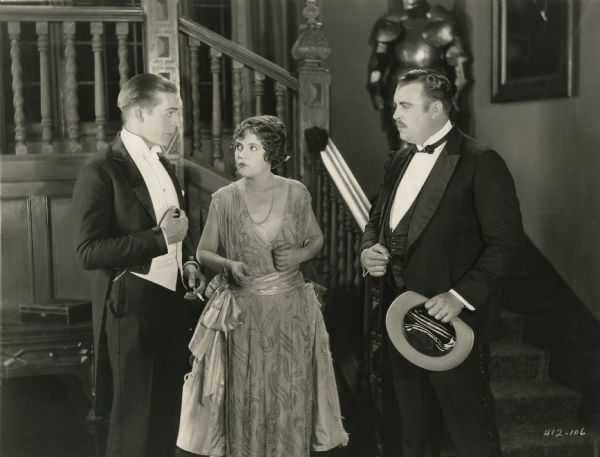 William Burroughs (played by Wallace Reid in formal evening wear and well-oiled hair) has a confrontation with Lord Brockingon (Stanley J. Sandford). Lady Elizabeth Galton (Lois Wilson) stands between them in a scene still from "The World's Champion" (1922).