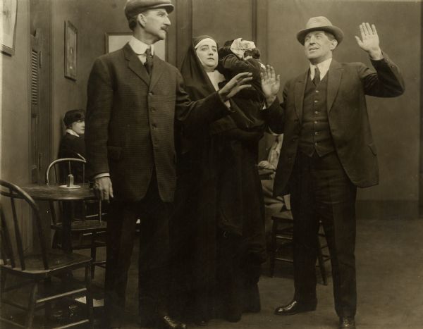 Roger Davis (left, played by Frank McGlynn Sr.) and Effie Dorgan (played by Miriam Nesbitt dressed as a nun and holding a child) with an unidentified actor in a scene still from the 1915 Edison production "A Woman's Revenge."