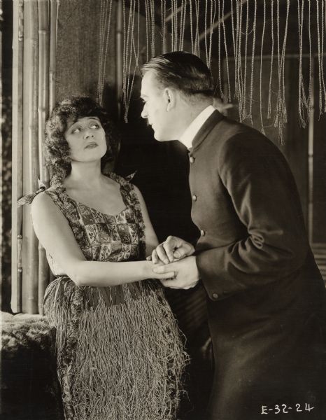 A missionary from New England, Winthrop Stark (played by William B. Davidson), professes his love to Princess Zara (Theda Bara in a grass skirt) on the South Sea island of Kolpee in a scene still from the 1919 Fox production "A Woman There Was."