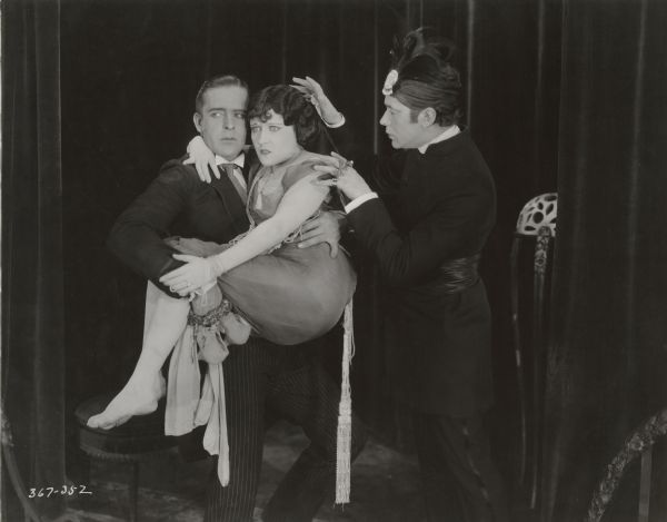 Anatol Spencer (played by Wallace Reid) carries his wife Vivian (Gloria Swanson) in his arms. She has been mesmerized by Nazzer Singh the Hindu hypnotist (played by Theodore Kosloff) in this scene still from Cecil B. DeMille's 1921 production "The Affairs of Anatol."