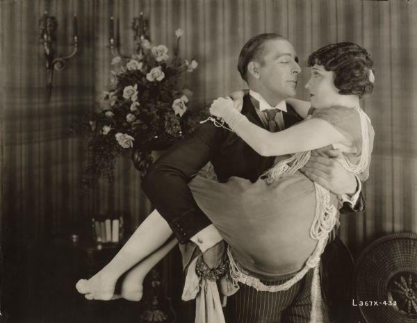 Anatol Spencer (played by Wallace Reid) carries his wife Vivian (Gloria Swanson) in his arms in this scene still from Cecil B. DeMille's 1921 production "The Affairs of Anatol."