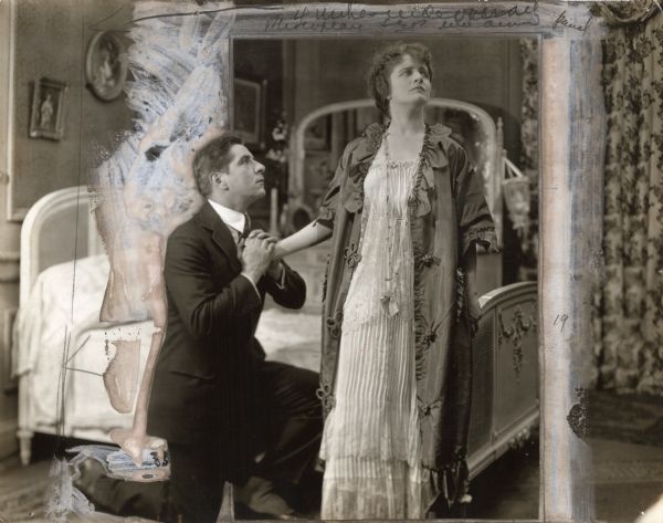 Jimmy Valentine (played by Robert Warwick) is down on one knee imploring forgiveness from Rose Fay (Ruth Shepley) in a heavily retouched scene still from "Alias Jimmy Valentine" (1915). Shepley wears a nightgown and robe.