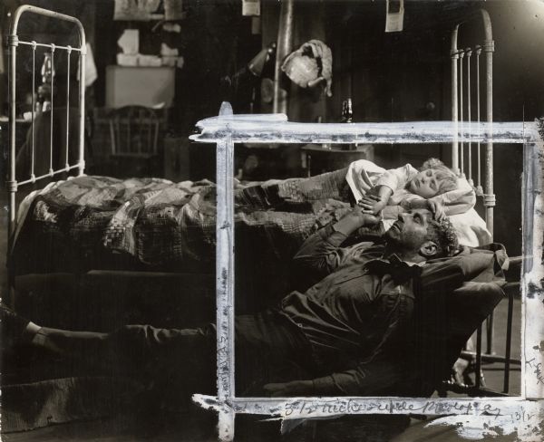 Jimmy Valentine (played by Robert Warwick) sleeps on the floor beside the bed of Rose Fay's baby sister (the child actress Madge Evans) in a heavily retouched scene still from "Alias Jimmy Valentine" (1915).