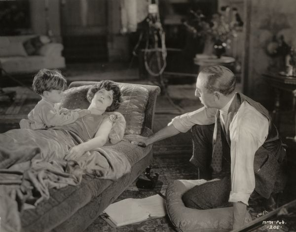 Seated on a cushion on the floor, Chester Franklin directs a tender scene with the child actor Mickey Moore (Michael D. Moore) and Mary Miles Minter in a production still for "All Souls' Eve."