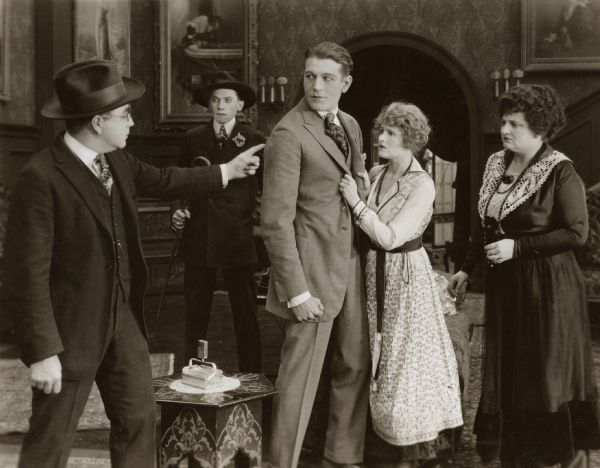 From left to right, the actors in this scene still from "The Amateur Adventuress" are Eugene Pallette, Victor Potel, Allan Sears, Emmy Wehlen, and Lucille Ward.