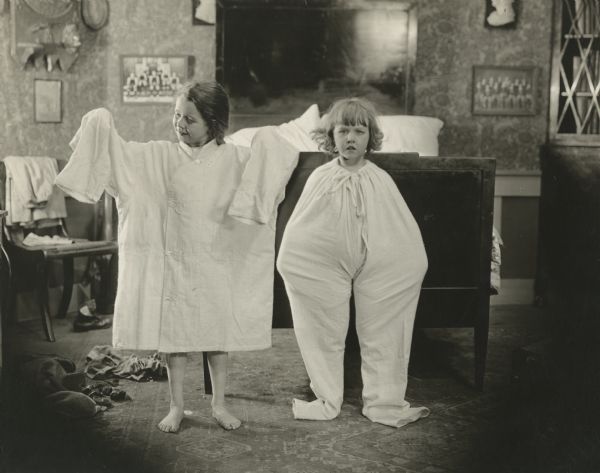 The child actors Jane Lee and her sister Katherine divide a man's pajama top and bottom between them in a cute scene still for "American Buds."