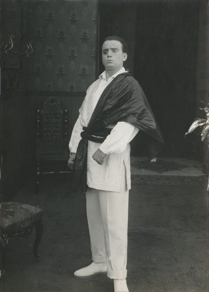 Douglas Fairbanks, wearing Mexican-style white trousers and shirt, poses in a publicity still for "The Americano." The caption on the reverse of the print reads: "About to throw the bull."